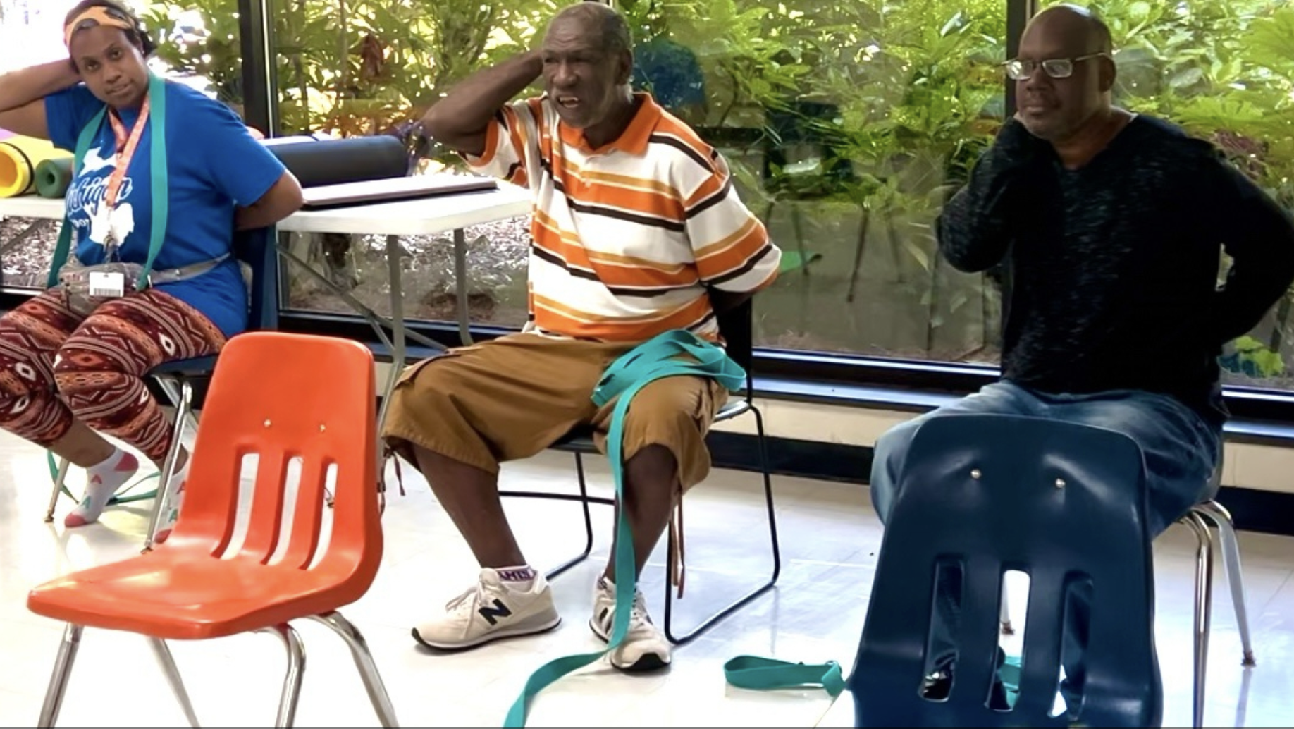 Students in Jane's Adaptive Yoga Class at an Adult Day Center practice a stretch behind their back